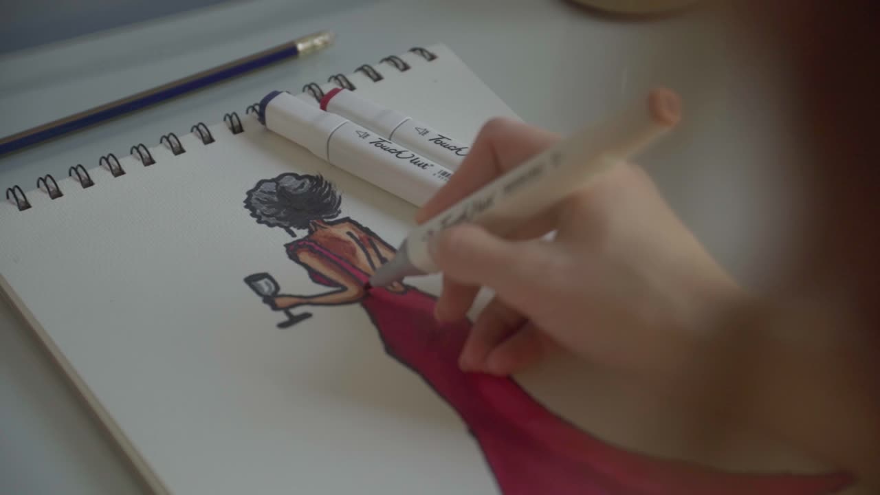 diseñadora de moda dibujando un vestido en un bloc de dibujo