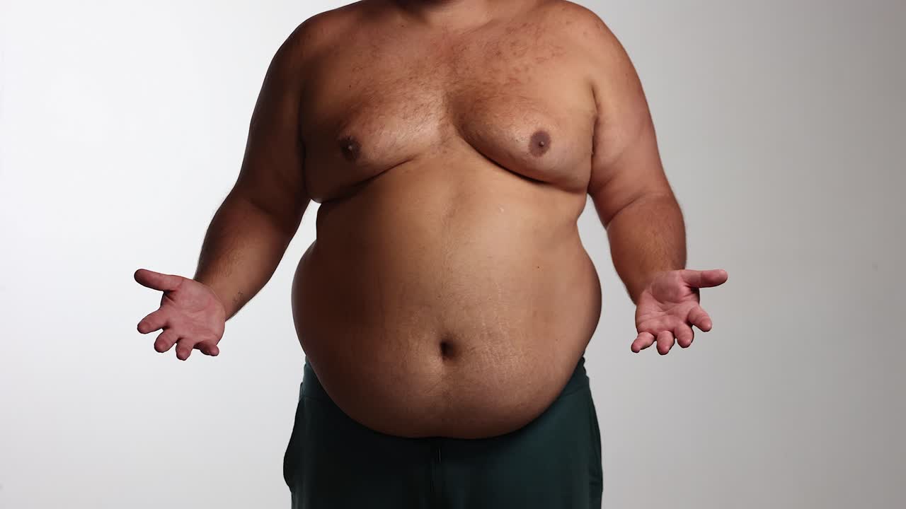 Overweight man shrugs against white background, weight loss goals