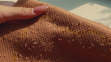 close-up of hand sewing on a brown fabric