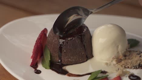 mano usando una cuchara para cortar un delicioso postre de lava volcánica de chocolate