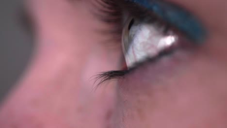 reflejo de la pantalla en el ojo azul-verde de la persona en una habitación oscura 23