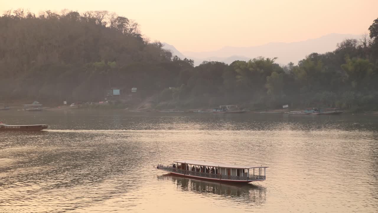 barco flotando por el río mekong al atardecer en luang prabang, laos viajando por el sudeste asiático