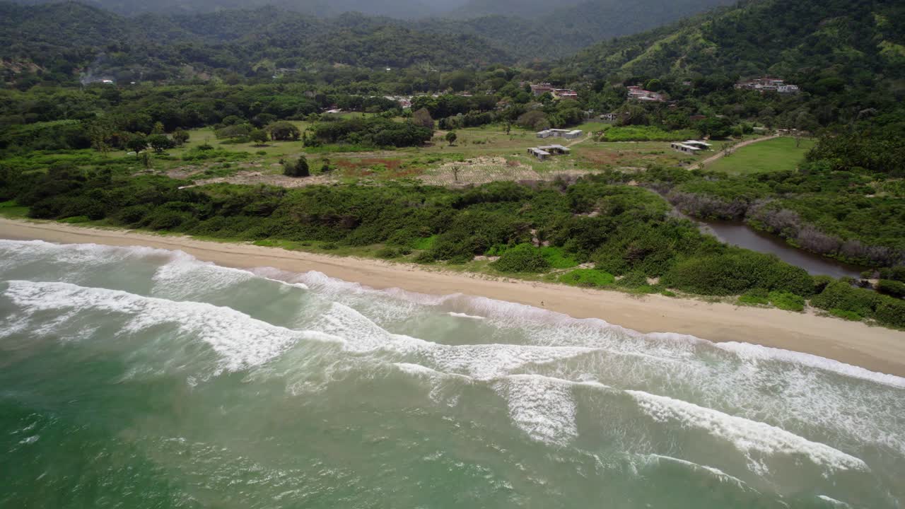 Green hills meet the Caribbean Sea as waves crash along the La Sabana beach shore