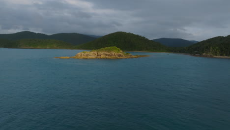 drone flying towards a small rocky island during sunrise in the whitsundays, qld, australia