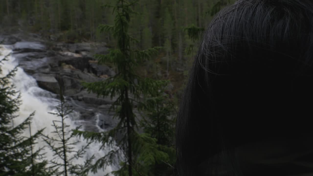 niña viendo una cascada dramática en el bosque