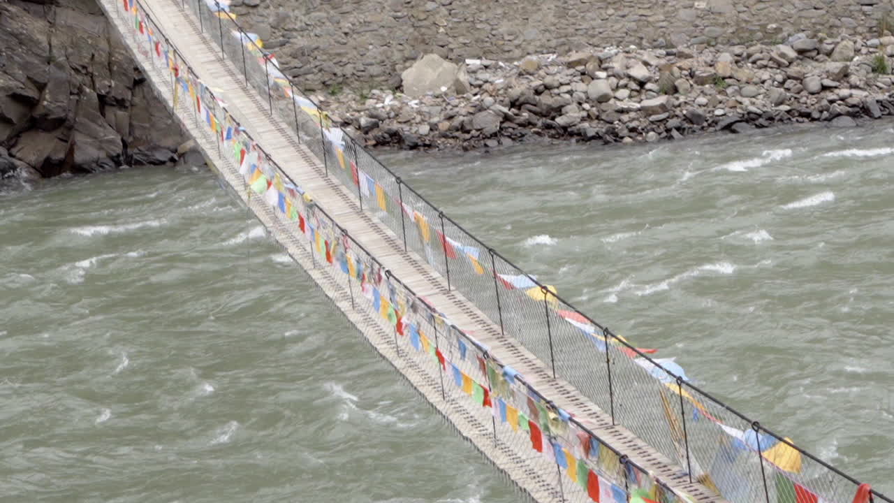 puente colgante tibetano decorado con banderas de oración multicolores cerca de la aldea montañosa de sichuan en china