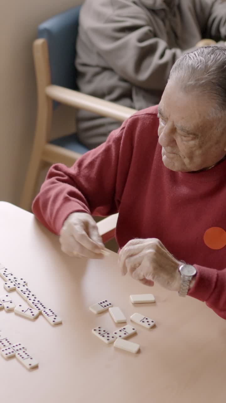 Senior man playing dominoes with old friend in a geriatric