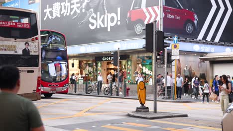 buses and pedestrians at a busy intersection