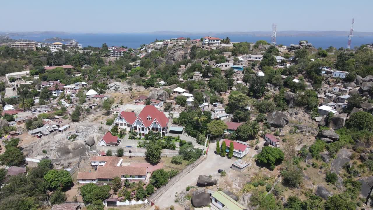 An HD tilting drone shot transitions from suburban houses to lush natural landscapes in Africa. Captures the harmony between urban living and the surrounding vibrant beauty of nature.