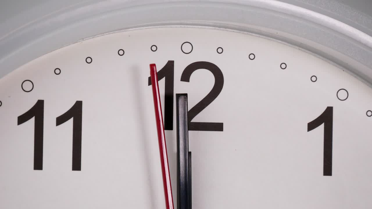 White wall clock tells the time 12 o'clock.