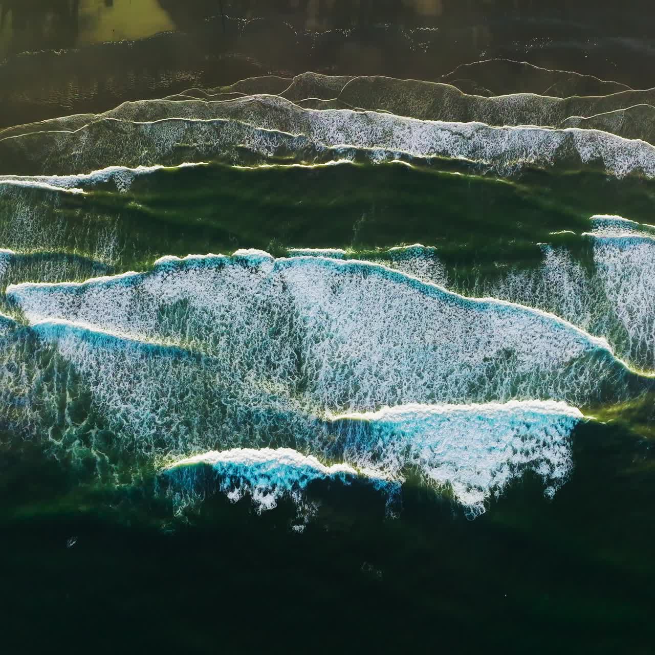 Amazingly beautiful foamy waves coming to the shore. Pleasing sight of wide tide covering the beach from bird's eye view