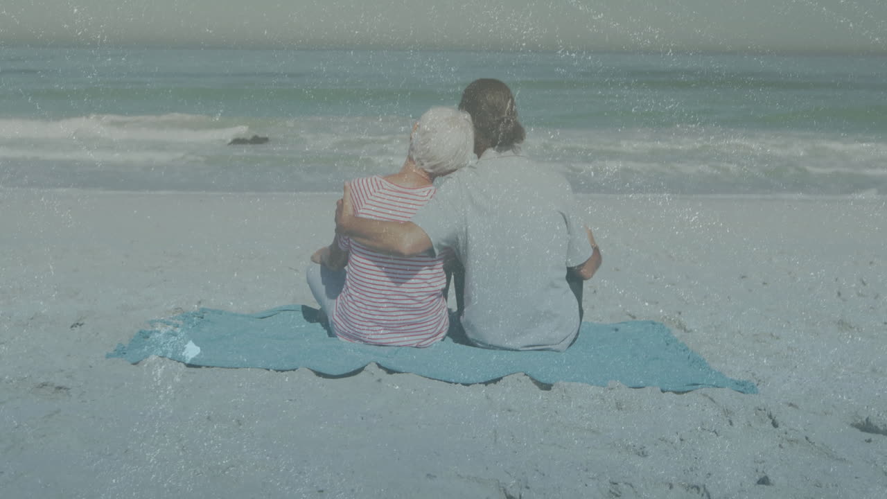 On beach, couple embracing while watching waves with animation overlay
