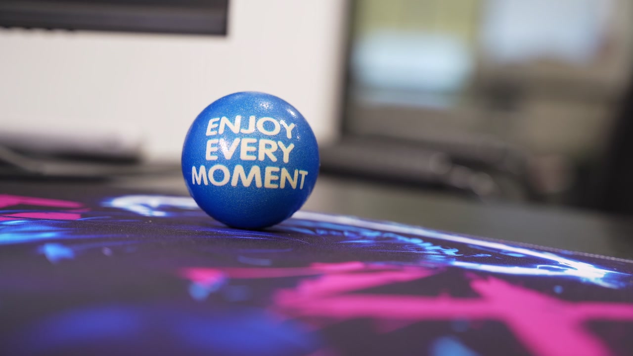 Close-up of a blue stress ball reading Take a Deep Breath on a colorful desk mat in a computer workspace, promoting calm, mindfulness, and emotional wellness.
