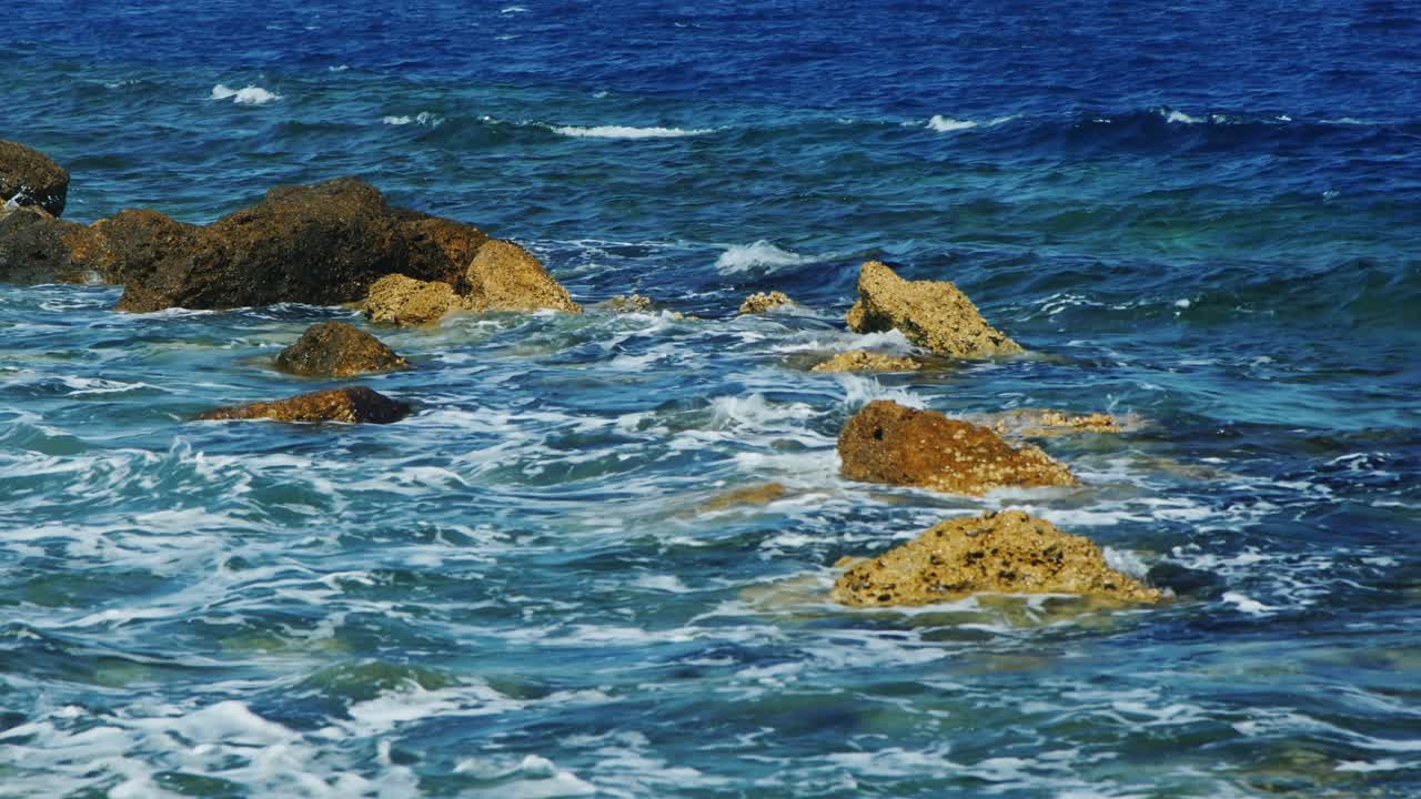Onde che si infrangono sulle rocce in una giornata di sole.
