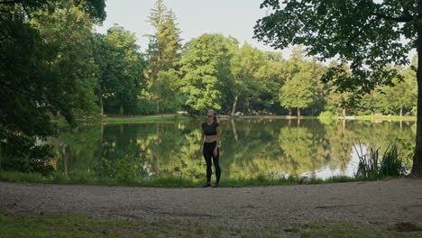 Mujer-Joven-Yoga,-Estiramiento-Junto-Al-Lago,-Calentamiento