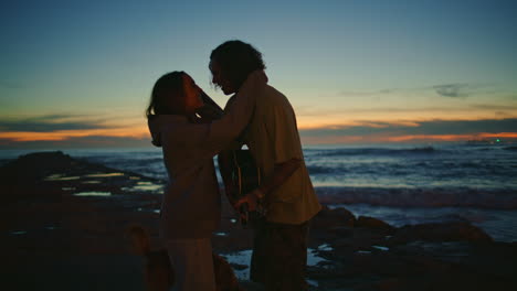 carefree couple dancing together evening beach. man playing guitar kissing girl