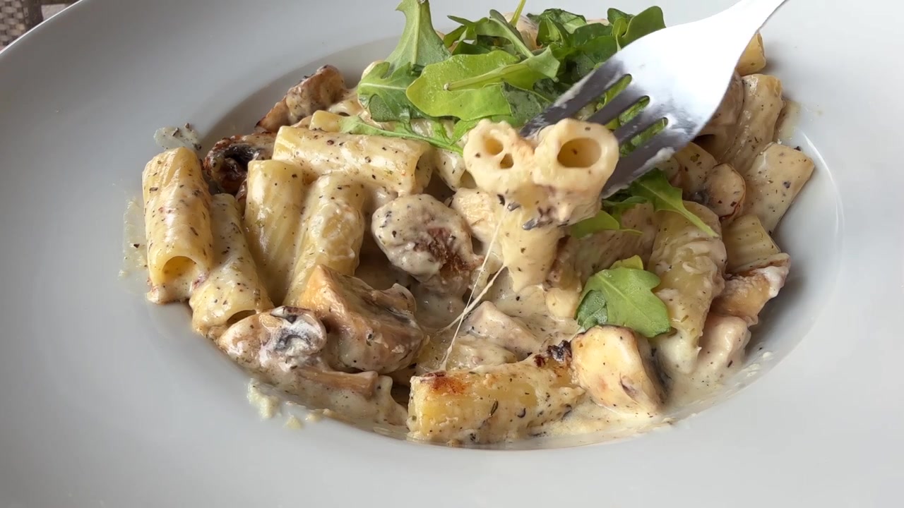 Mangiare pasta con pollo e funghi con salsa cremosa bianca ai funghi, primo piano.