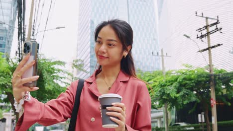 woman with coffee cup using mobile phone in city