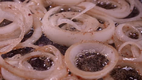 full frame closeup: onion rings fry, sizzle in hot oil in frying pan