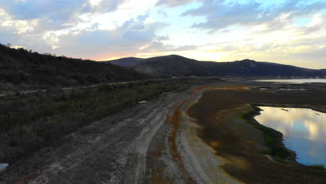 un dron aéreo sale volando desde la orilla seca con anillos de bañera hasta una toma más amplia del lago irvine en el sur de california en la hermosa puesta de sol- el lago está casi vacío debido a la sequía