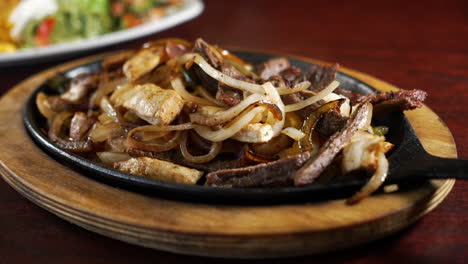 a sizzling cast iron skillet of combination beef and chicken fajitas with grilled onions and peppers, slider 4k