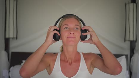 blond woman puts on headphones, listen to music and swaying head, carefree