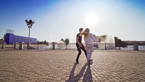 young dancers moving in tact. boy and girl dancing together outdoors. beautiful couple dancing an energetic dance on fountain background.
