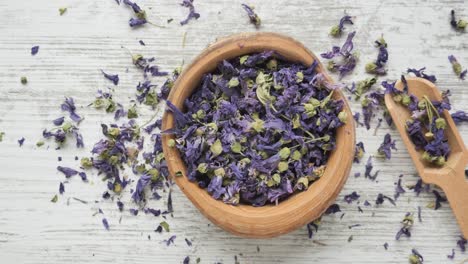 dried violet flowers in wooden bowl