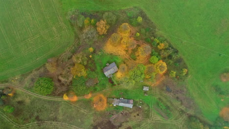 aerial drone top down shot of cottages surrounded by green grasslands at daytime