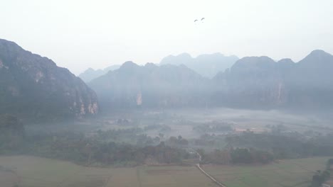 Disparo-De-Niebla-Por-Drones-Durante-La-Mañana-Brumosa-En-Vang-Vieng,-La-Capital-De-Aventuras-De-Laos