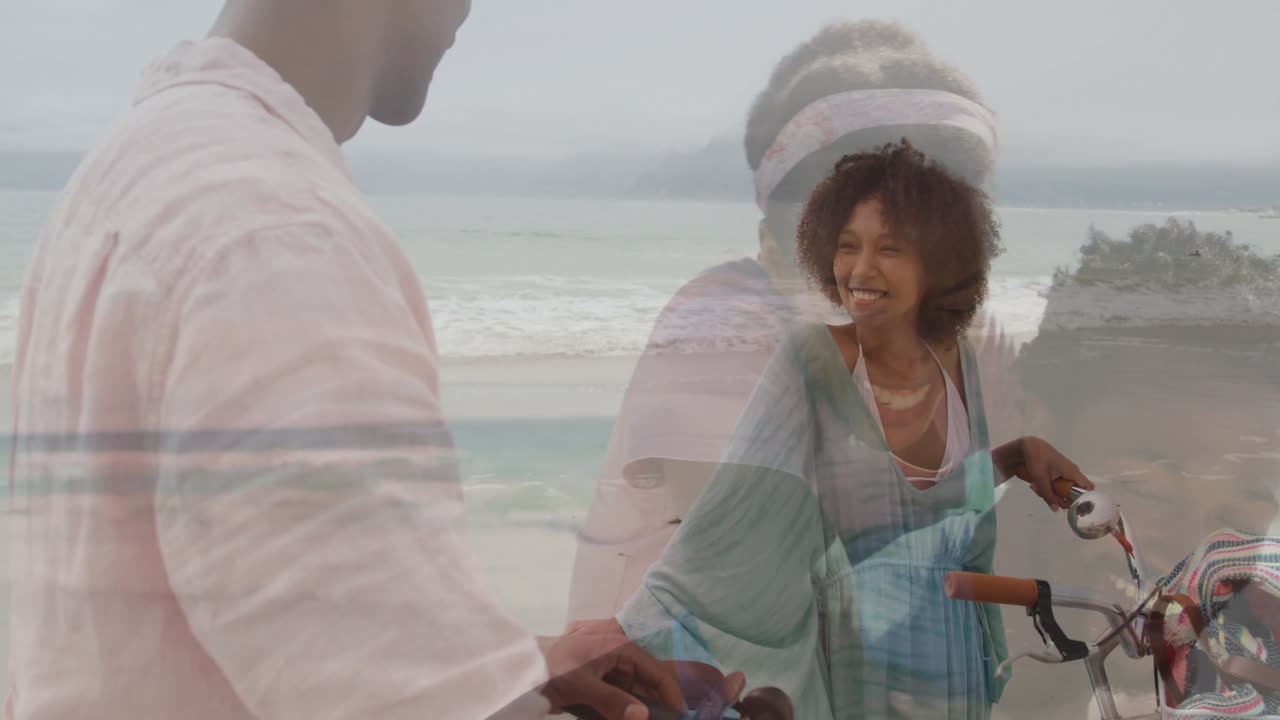 Riding bicycles along beach, smiling couple with ocean waves in background