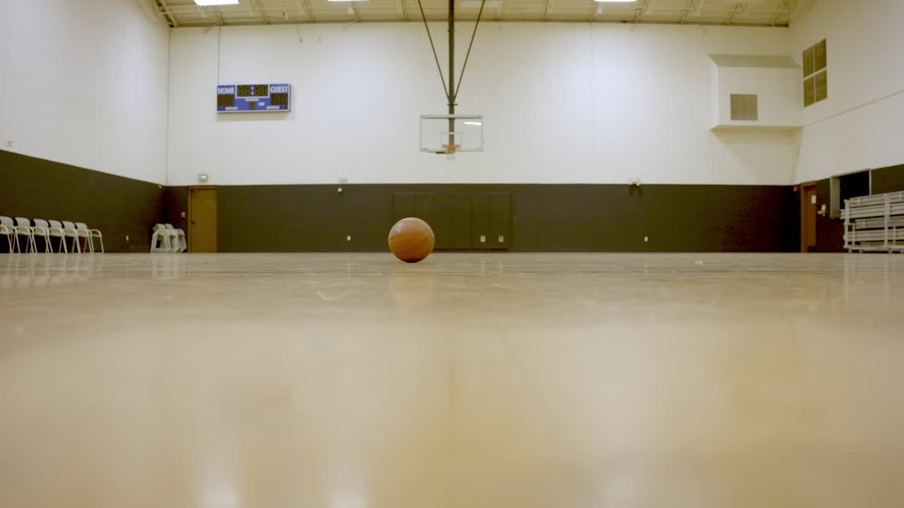 pelota de baloncesto rodando por el suelo de una cancha de baloncesto vacía, tiro estático