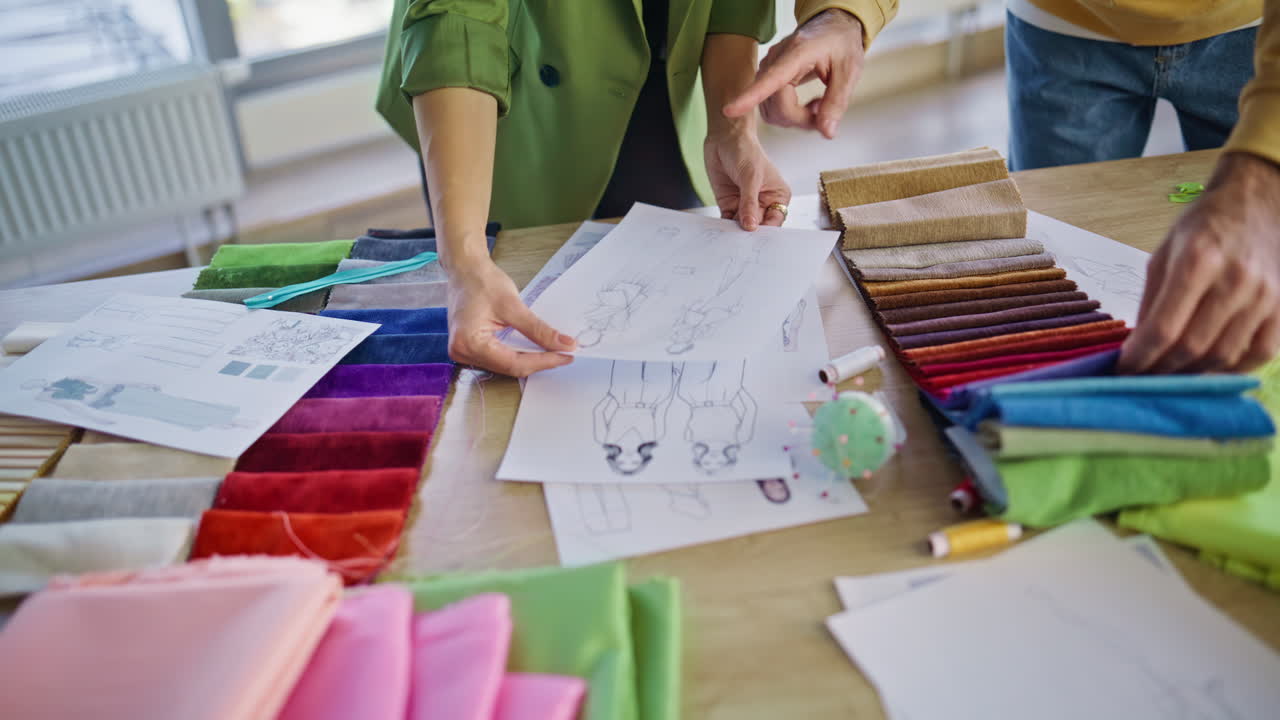 Stylists hands choosing cloth samples for fashion collection in office closeup