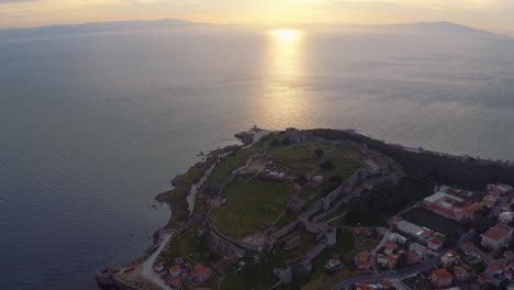 aerial drone flight over mitilini castle, lesbos revealing sunrise at sea looking at athens, lesvos, greece