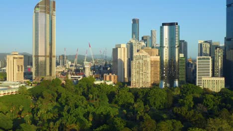 Vista-Aérea-De-La-Ciudad-De-Brisbane-Cbd-Detrás-De-Los-Jardines-Botánicos-Y-Las-Grúas-Del-Sitio-De-Construcción-Del-Muelle-De-La-Reina-Visibles,-Qld,-Australia