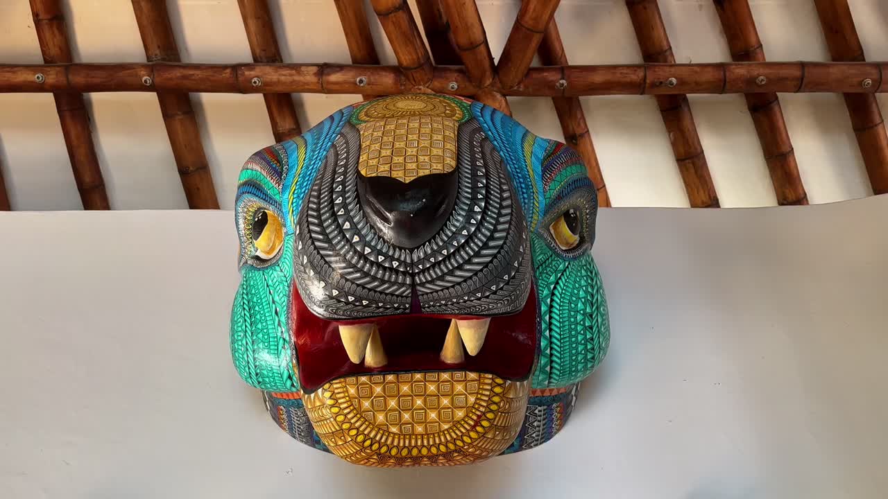 Scultura colorata di una maschera da giaguaro esposta sulla parete interna di una villa