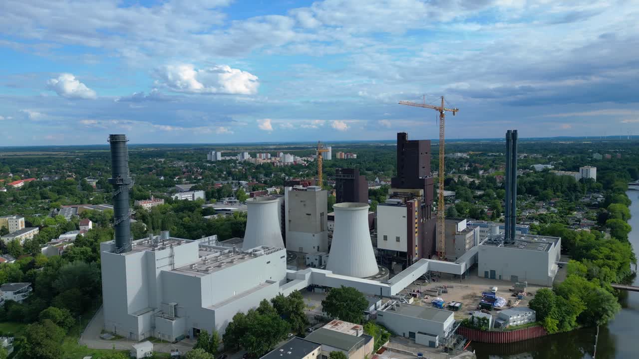 Power plant undergoing conversion, retrofitting and renewal, featuring cooling towers, chimneys, and construction crane. Lovely aerial view flight fly push forward drone