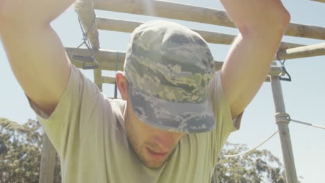 soldado caucásico cansado colgado de barras de mono en una carrera de obstáculos al estilo del ejército en el sol