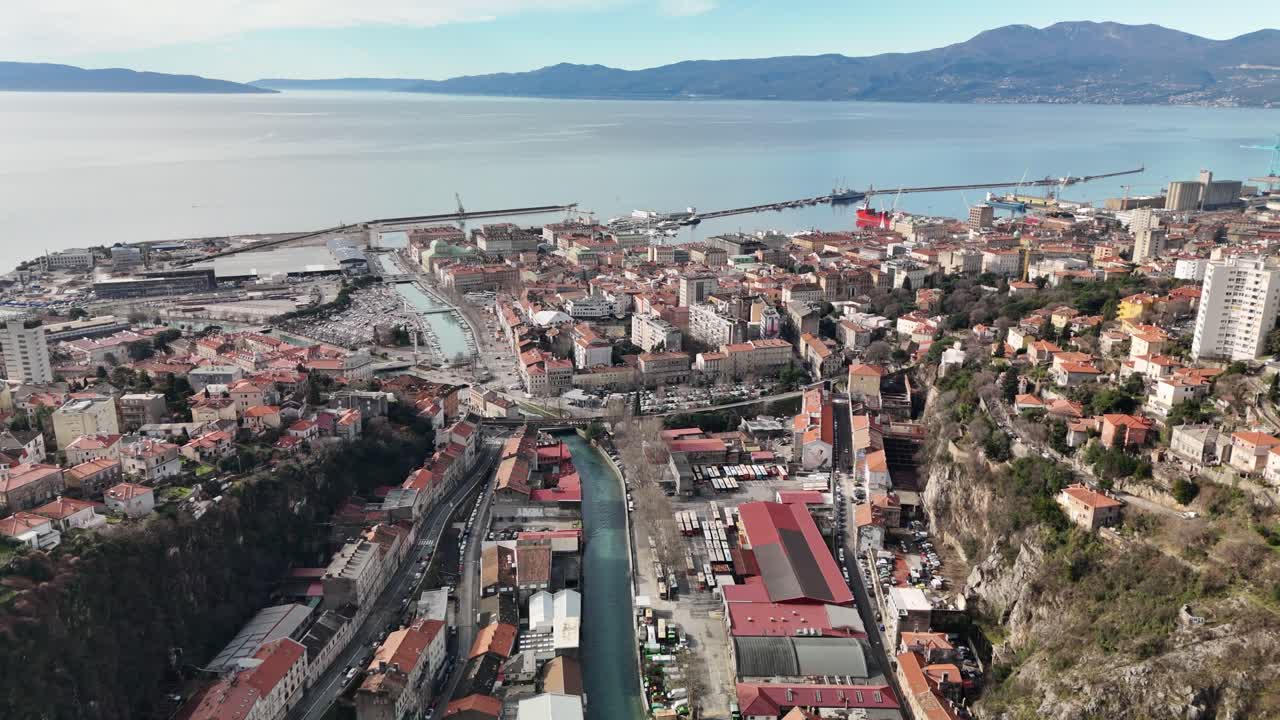 Drone aereo che sorvola il fiume Rječina attraverso Fiume verso la Baia del Quarnaro e il Mare Adriatico in una giornata di sole. Paesaggio urbano che si estende sotto con la costa e la baia in lontananza.
