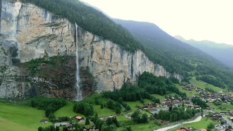 flying to the famous waterfall spissbachfall in lauterbrunnen grindelwald of switzerland with its forrestry landscape, alp mountains, and the village at its foot during summer time