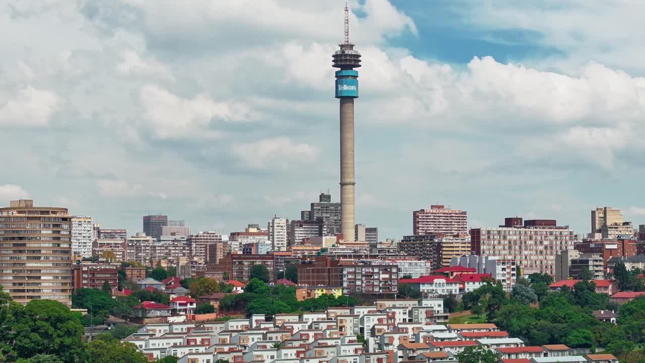 Splendido timelapse aereo in 4K del paesaggio urbano di Johannesburg a mezzogiorno. Alberi verdi, veicoli in movimento e nuvole dinamiche sopra lo skyline della città sudafricana