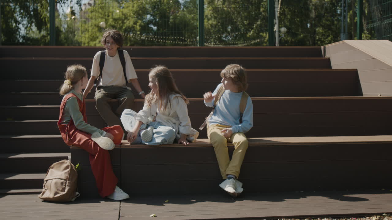 Children with backpacks socializing on outdoor steps