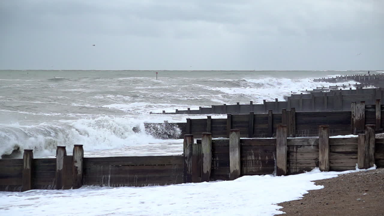In slow motion large and threatening waves break against groynes on the beach as storm Ciar&aacute;n makes landfall