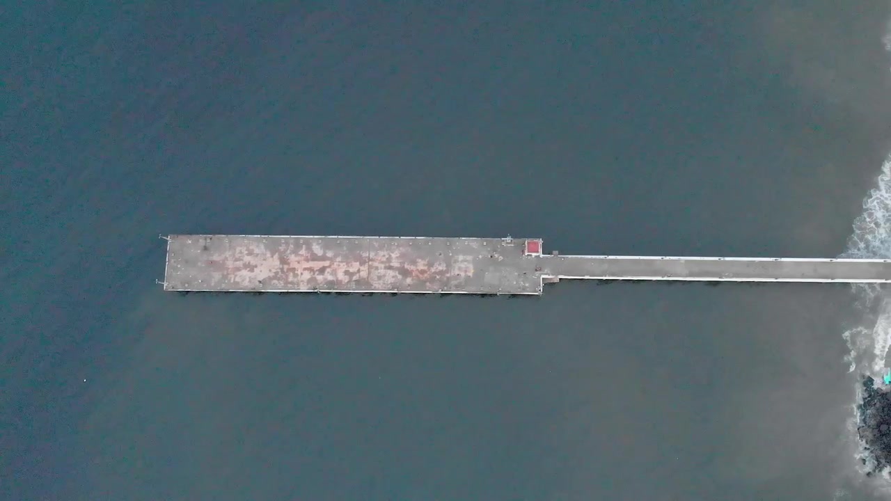 4k Aerial Top Down Panning shot from Right to Left of a Shipping Port Pier on a Sunrise with monsoon clouds covered near Rock Beach shot with a drone, Pondicherry, India