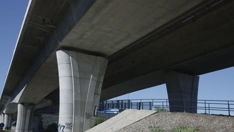 wide shot of mountain biker cycling under concrete bridge