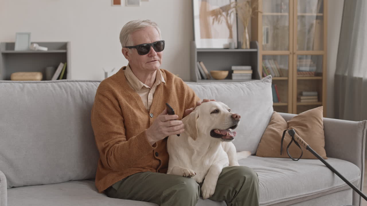 Blind Man Holding Smartphone Next to Dog at Home