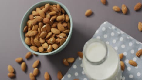 video de almendras de frutas frescas en un tazón y una botella de vidrio de leche sobre un fondo gris