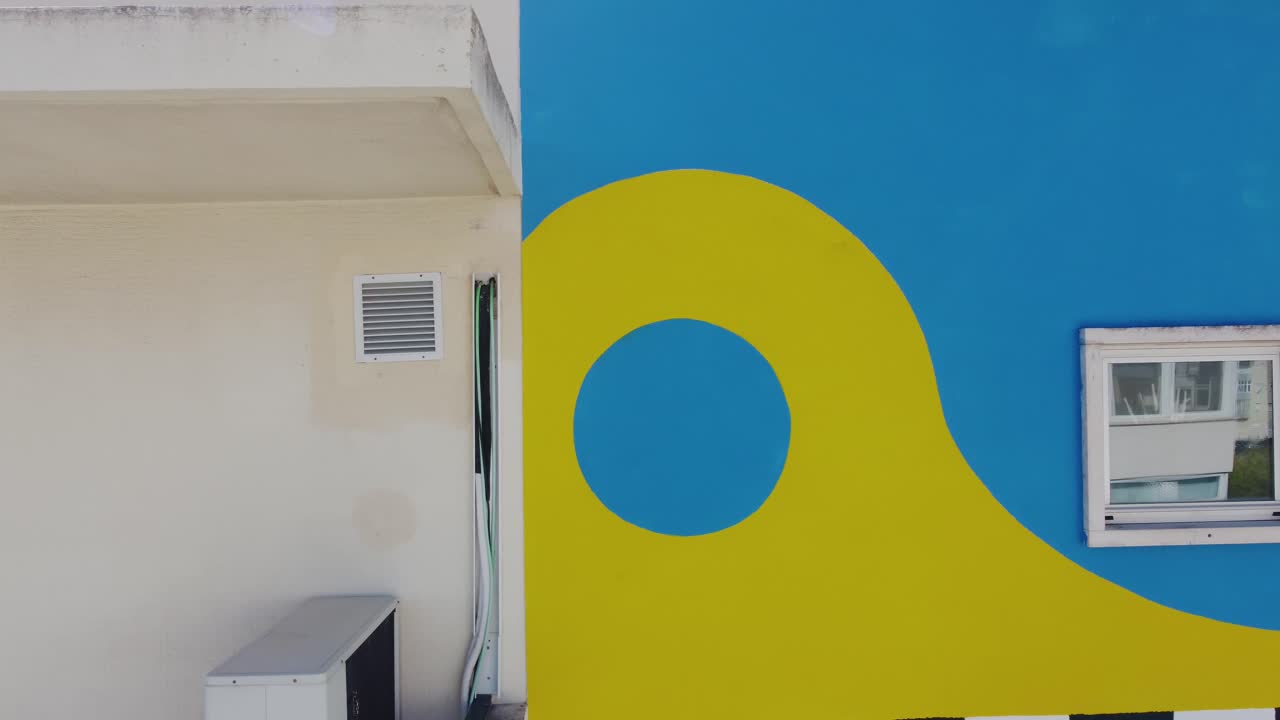 el vuelo del avión no tripulado se desliza graciosamente horizontalmente a lo largo de la pared lateral de un edificio residencial, capturando un lienzo vibrante de pinturas de graffiti coloridas