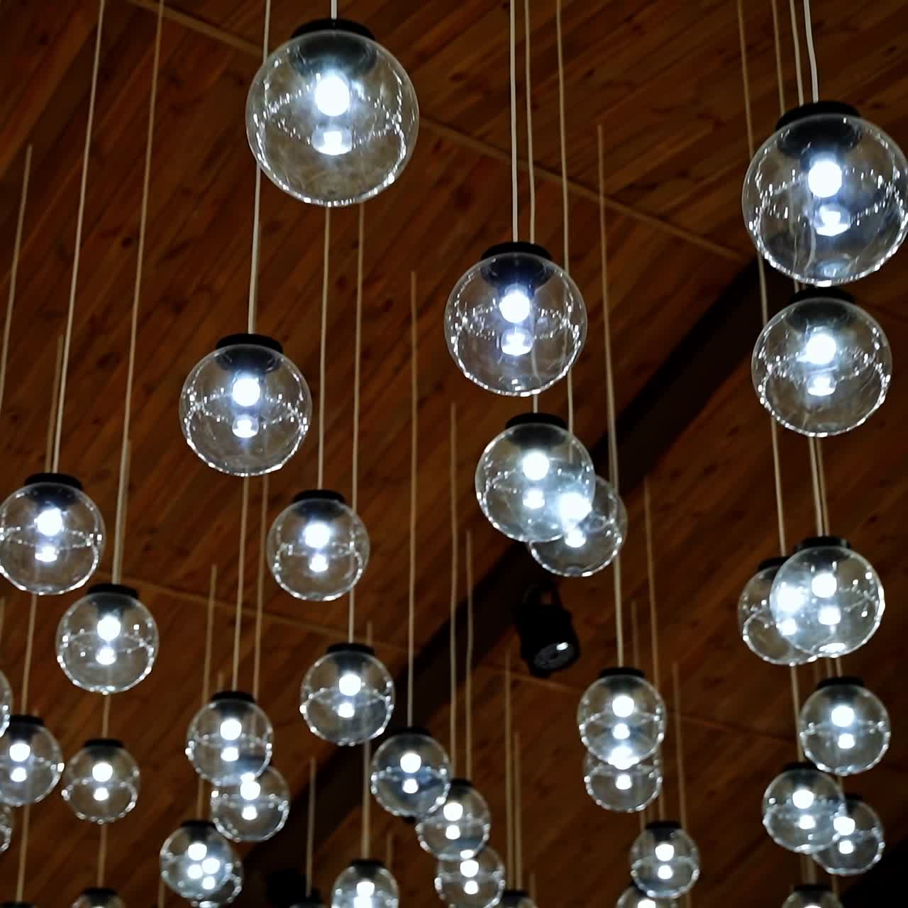 Modern ceiling design. Shining glass balls hanging from the top. Interior of glowing round lamps on white wires.