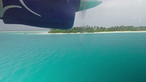 window view of seaplane engine getting lower to water for landing, maldives